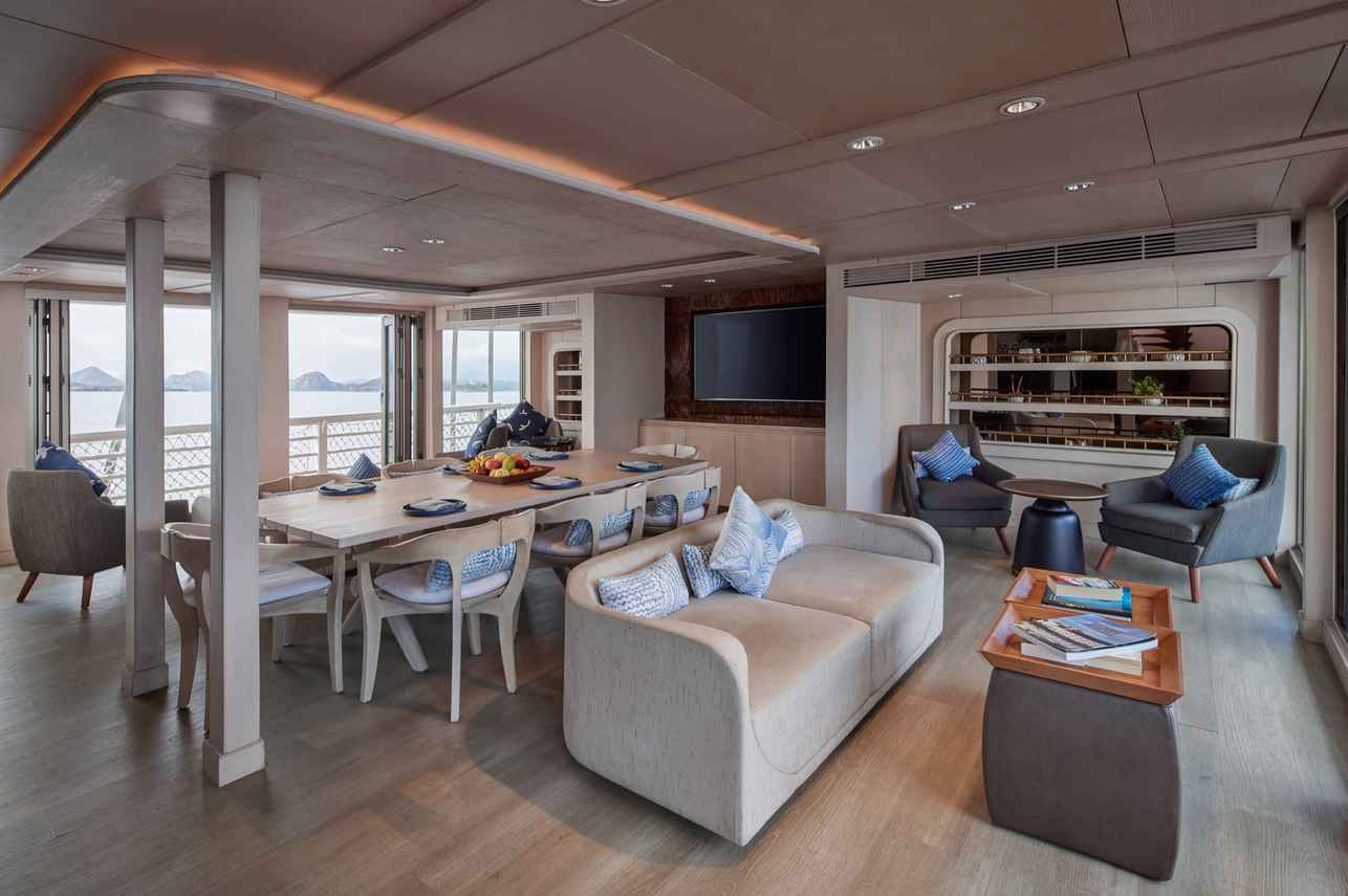 Luxury indoor living and dining area aboard a modern phinisi cruise Indonesia, featuring elegant seating, spacious dining table, panoramic ocean views, and refined interior design for an exclusive sailing experience.